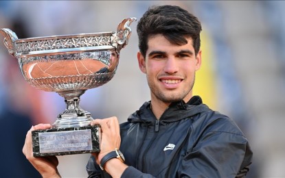 <p><strong>GRAND SLAM.</strong> Carlos Alcaraz of Spain celebrates victory with the trophy after the Men's Singles Final match of the 2024 French Open against Alexander Zverev of Germany on Sunday (June 9, 2024) in Paris. Alcaraz made history by becoming the youngest ever to win a major trophy on hard courts (US Open 2022), grass courts (Wimbledon 2023), and clay courts (French Open 2024). <em>(Anadolu photo)</em></p>